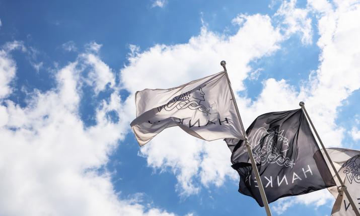 Hankens flaggor vajar i vinden mot en blå himmel med lite moln.