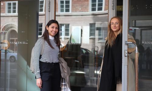 Two students standing at the main entrance of Hanken