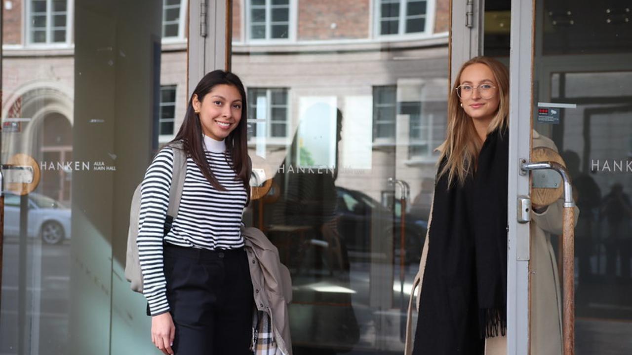 Two students standing at the main entrance of Hanken