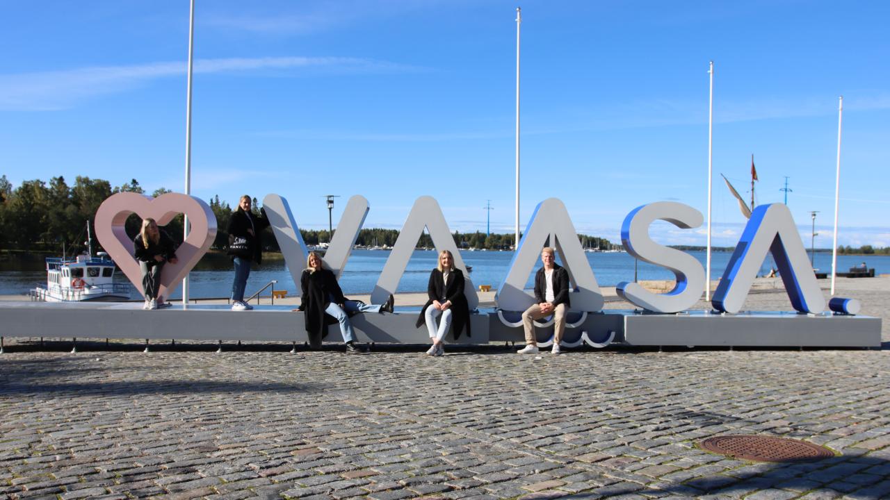 Studenter sitter vid en skylt där det står Vaasa och ett hjärta
