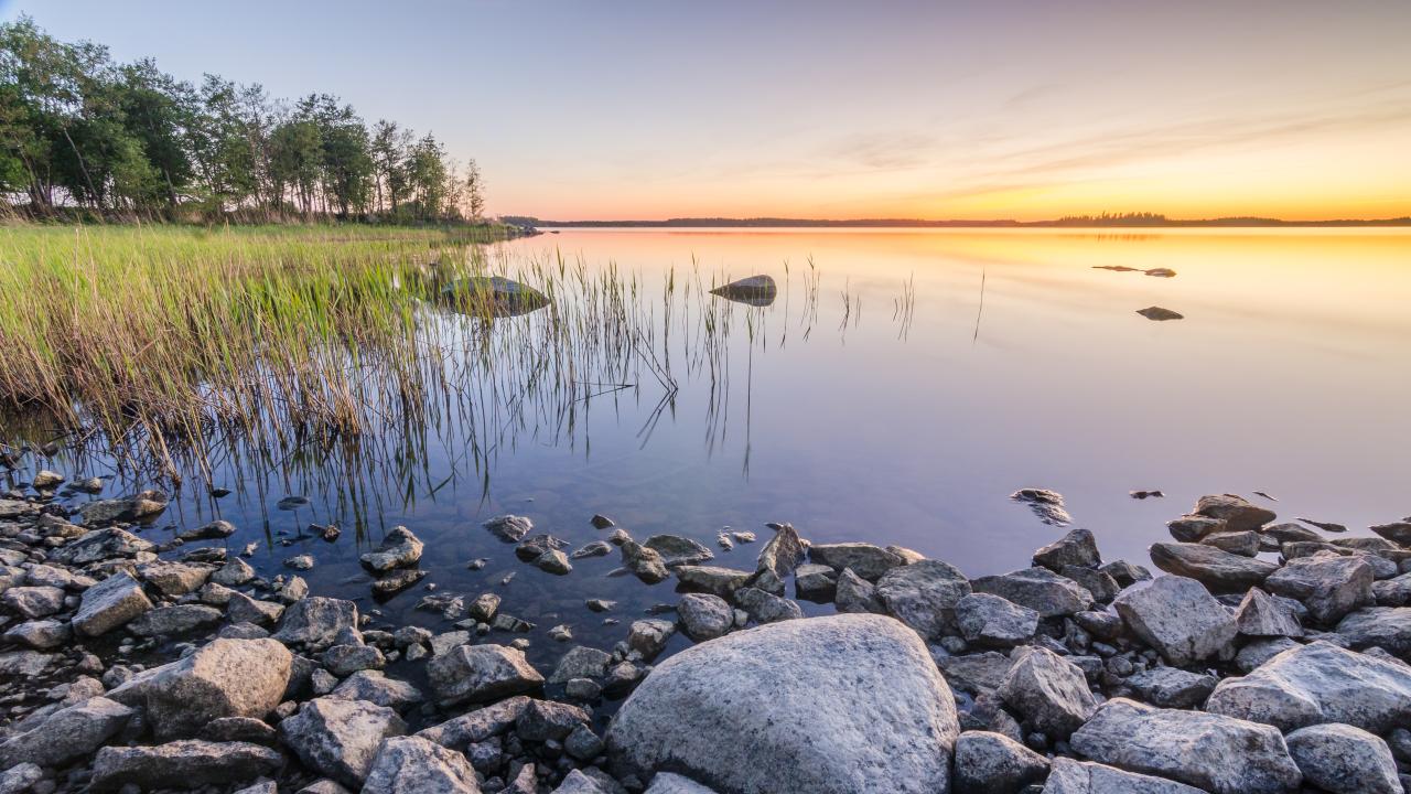 Solnedgång vid en stenig strand