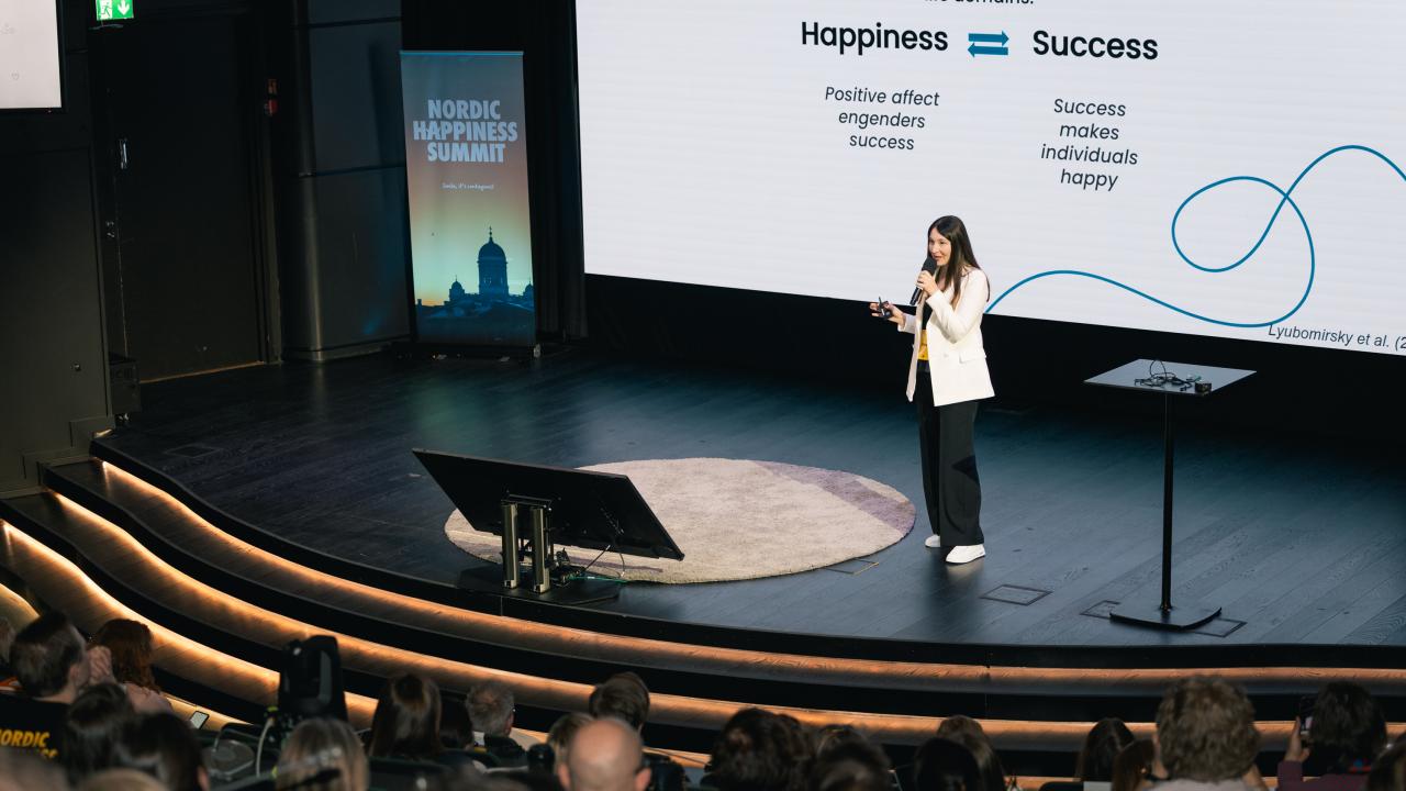 Forskare Alina Ianioglo på scenen under evenemanget Nordic Happiness Summit