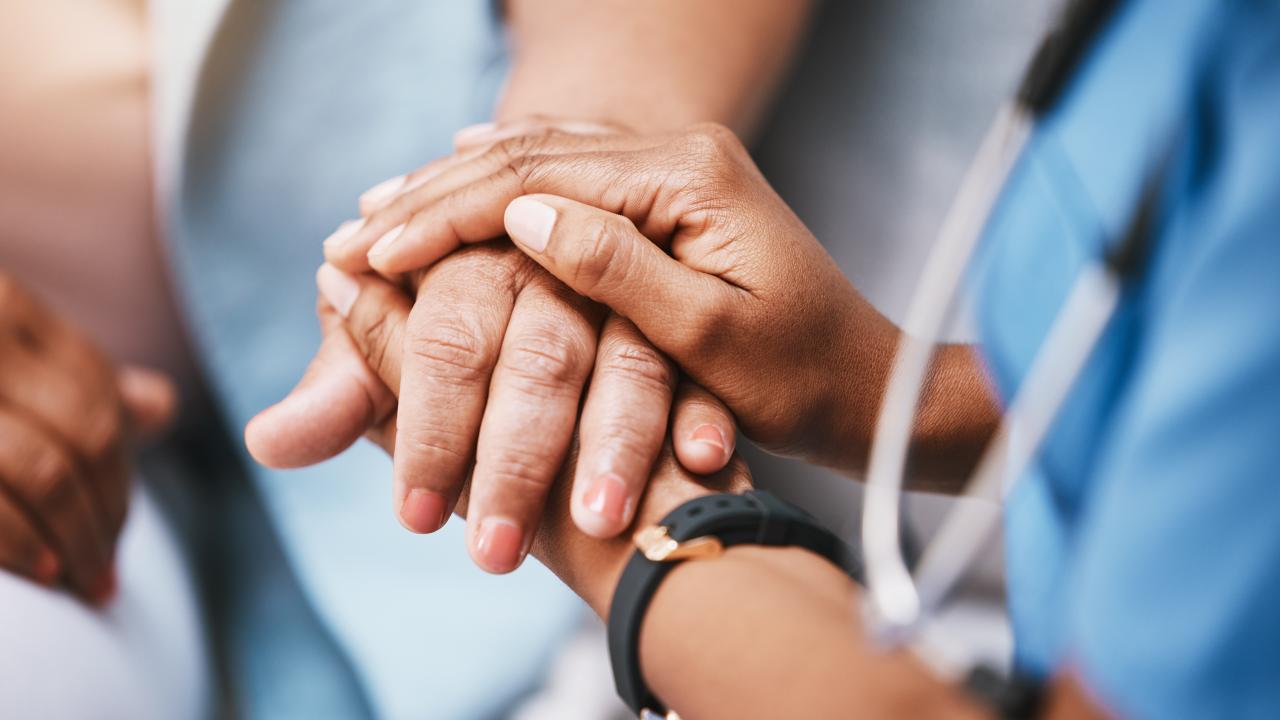 En vårdare håller en patients händer i sina händer