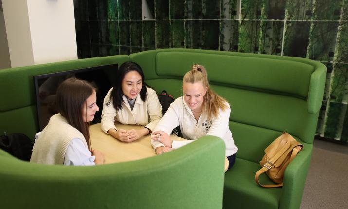 Students sitting at a table looking at a laptop