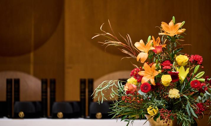 Flower arrangement with doctoral hats in background