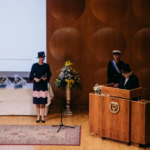 Estlands president Kersti Kaljulaid står på scenen i festsalen med sin doktorshatt och sitt diplom.