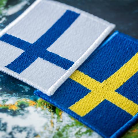 Finlands och Sveriges flaggor ovanpå en världskarta.