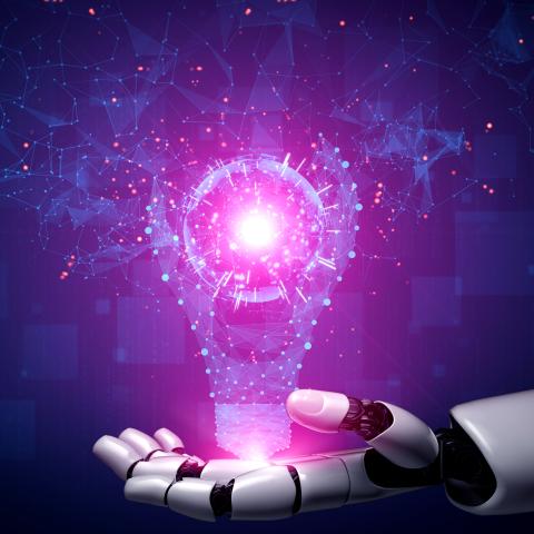En robotliknande hand håller i en glödlampa som lyser upp en mörk bakgrund
