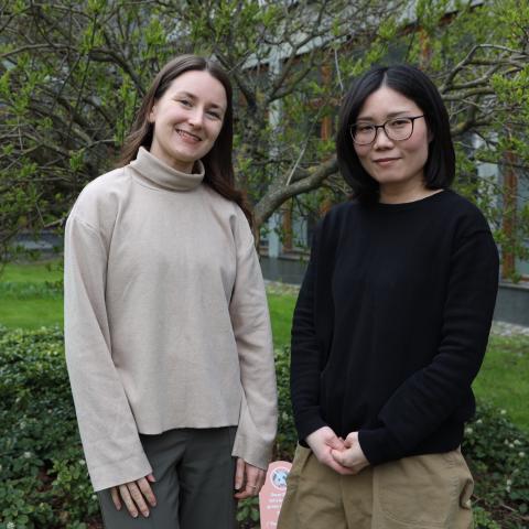 Hankenstudenterna Emma Richardson och Rie Koshida står bredvid varandra framför ett träd på Hankens gård.