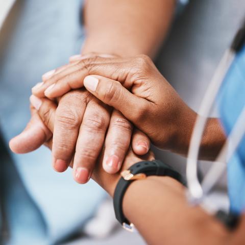 En vårdare håller en patients händer i sina händer