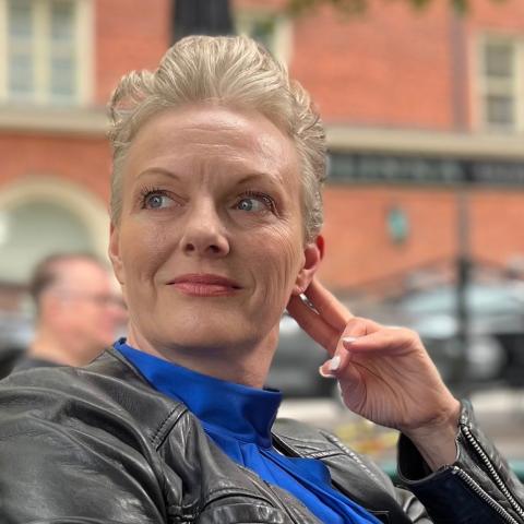 Portrait picture of Johanna Söderström sitting outside on an outdoor restaurant area.